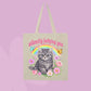 Beige canvas tote bag featuring a grumpy grey kitten, rainbow, flowers, butterflies, and pink text that says Silently Judging You.
