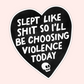 Black heart-shaped sticker with bold white lettering reading “Slept like shit so I’ll be choosing violence today” and a small skull.