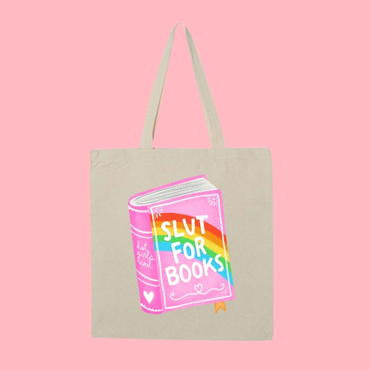 Beige tote bag with a colorful pink and rainbow book illustration that says “Slut for Books.”