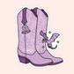 A die-cut sticker featuring a pair of lavender cowboy boots with a small purple dragon and sparkles, shown on a pale pink background.