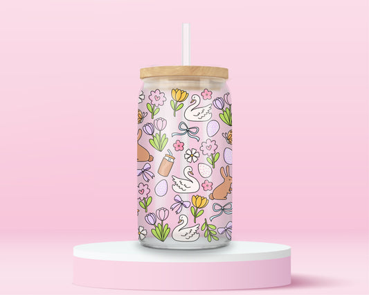 Pink glass tumbler with swans, bunnies, flowers, bows, and Easter eggs in a pastel spring pattern.