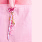 Strawberry beaded purse charm keychain with pink bow clip, pastel beads, and strawberry charm attached to a pink tote bag