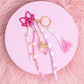 Strawberry purse charm keychain with pink and purple beads, daisy accents, and bow clip displayed on pink aesthetic background