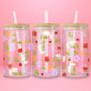 Glass can tumbler with bamboo lid and glass straw featuring strawberries, daisies, pastel flowers, green leaves, ladybugs, and lavender bow details on a pink background.