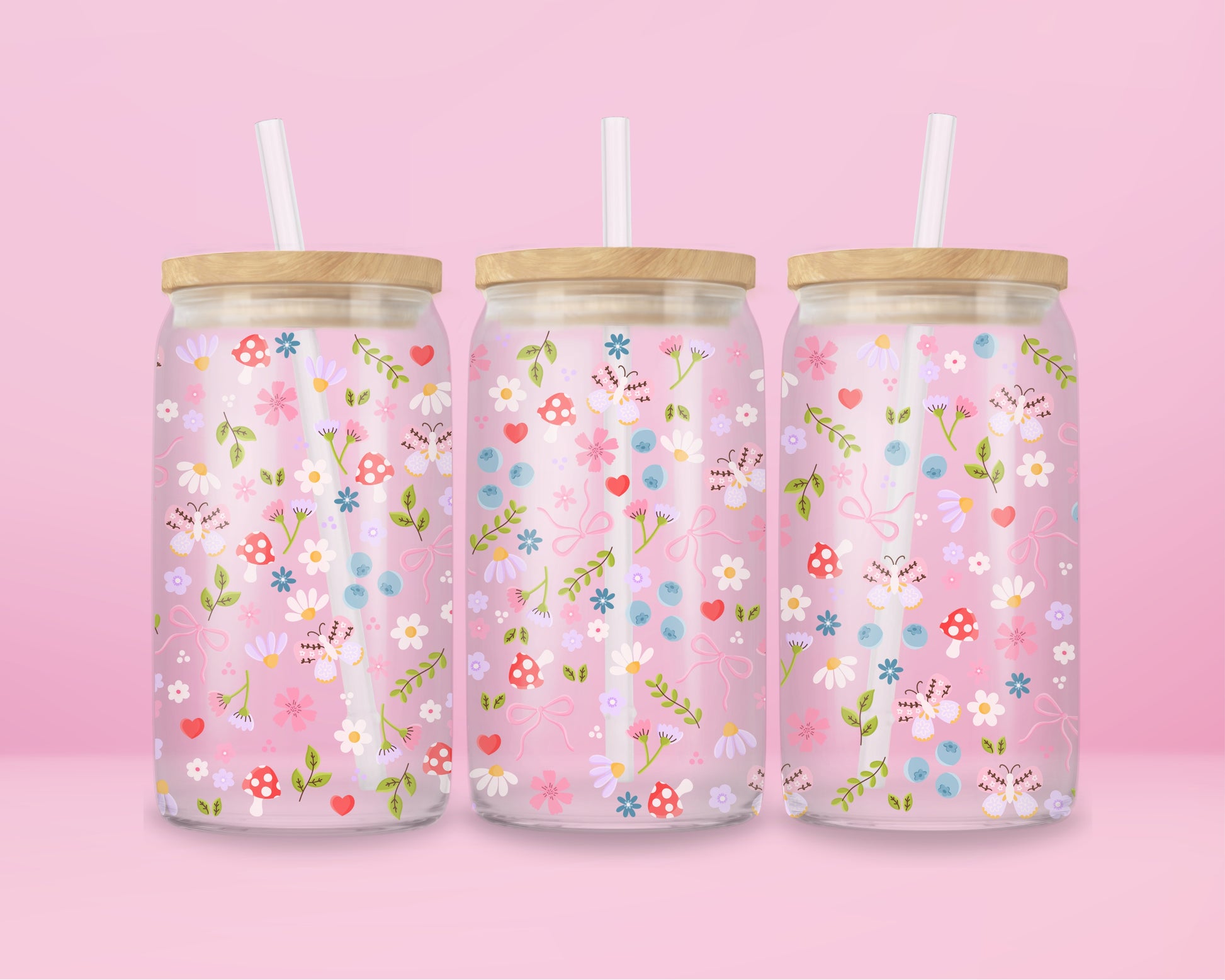 Glass can tumbler with bamboo lid and glass straw featuring a pastel floral, mushroom, blueberry, bow, and heart design on a pink background.