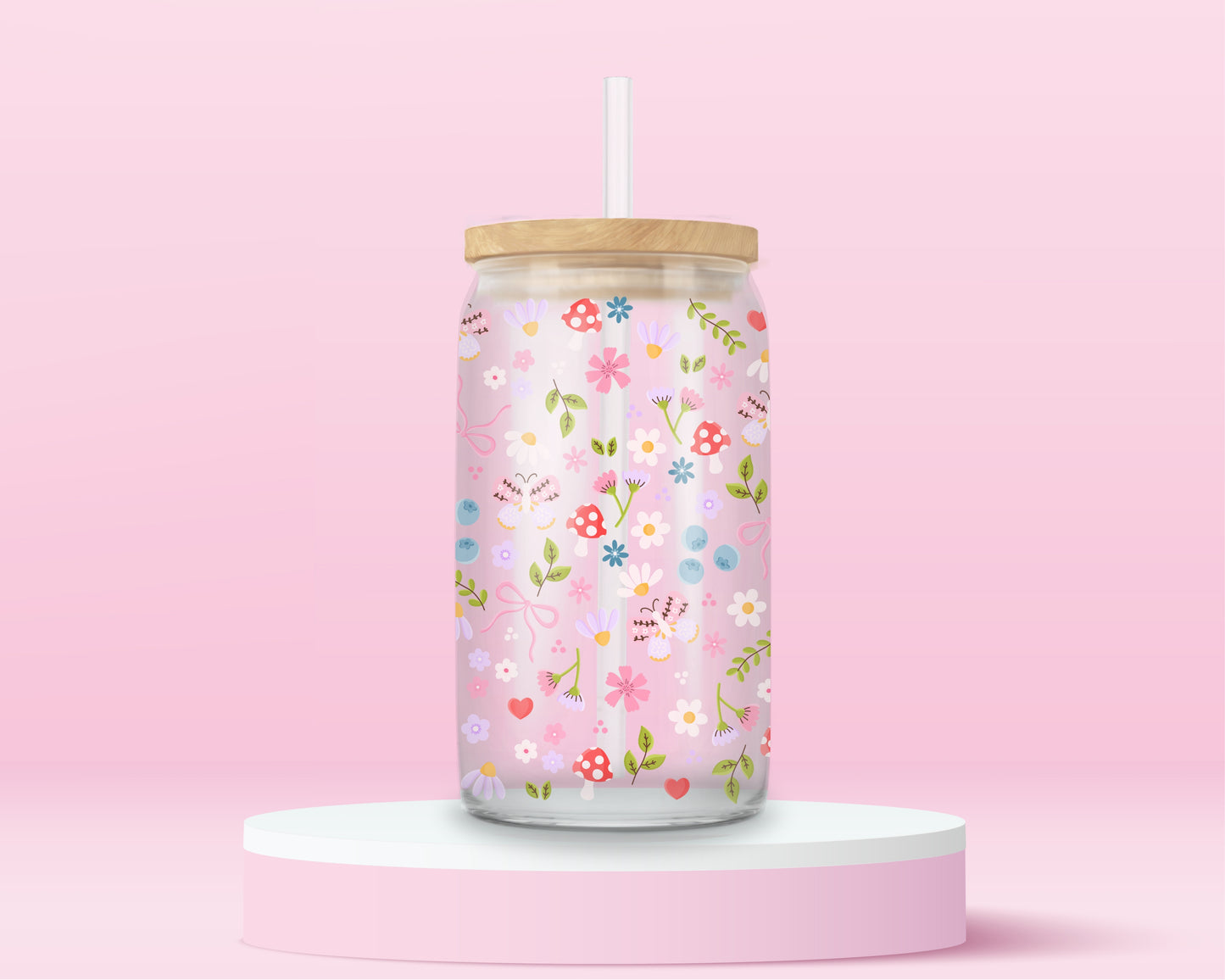 Glass can tumbler with bamboo lid and glass straw featuring a pastel floral, mushroom, blueberry, bow, and heart design on a pink background.