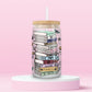 glass tumbler with stacked books labeled Taylor Swift albums like Fearless, Red, 1989, Folklore, Midnights, surrounded by flowers and butterflies.