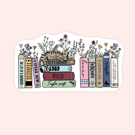 Sticker of a cat laying on books labeled with Taylor Swift albums, decorated with flowers.