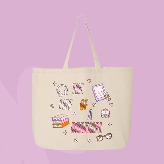 Beige tote bag with colorful pastel doodles of books, headphones, glasses, a candle, and text that says “The Life of a Bookgirl.”