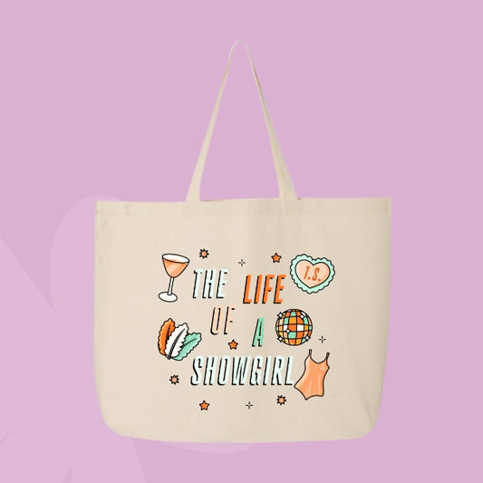 Beige tote bag with colorful doodles like a disco ball, cocktail, corset, and heart with “T.S.” text that says “The Life of a Showgirl.”