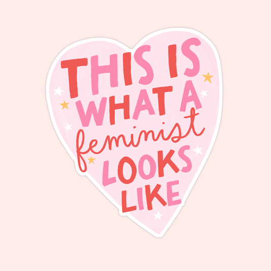 Pink heart-shaped sticker with the phrase "This is what a feminist looks like" in red and pink lettering.