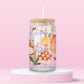 Glass can tumbler with bamboo lid and glass straw featuring an orange cat, mushrooms, bluebell flowers, ladybugs, leafy stems, and woodland cottagecore illustrations on a pink background.