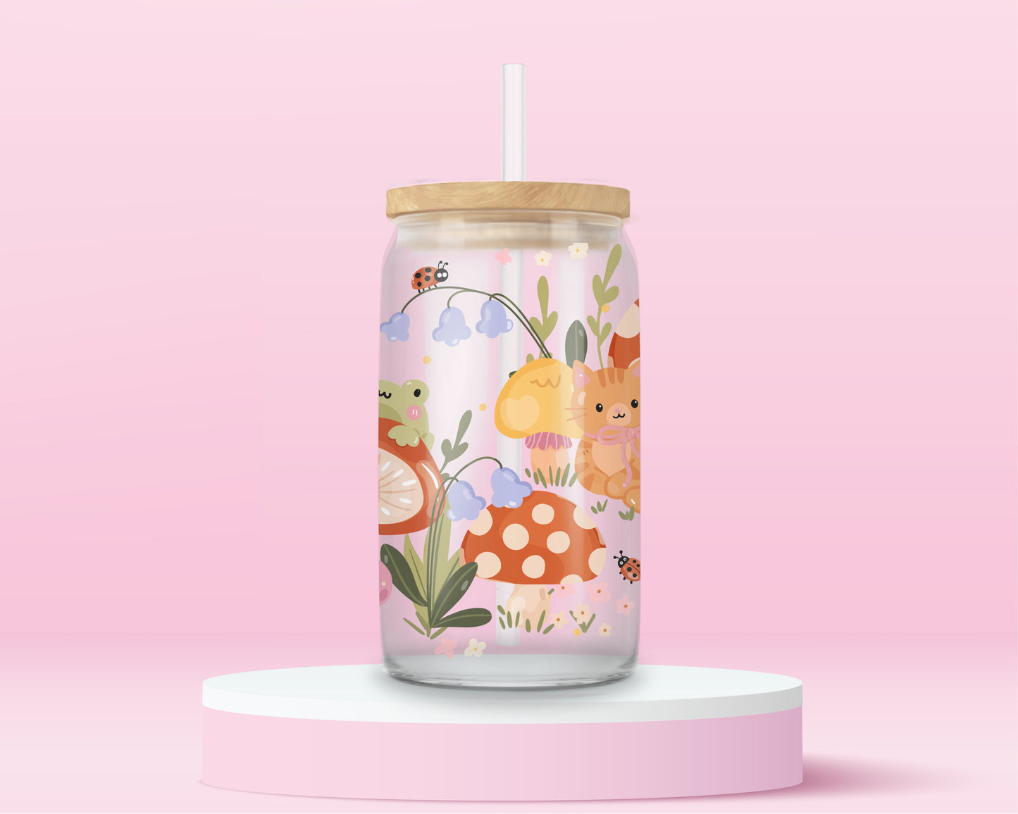 Glass can tumbler with bamboo lid and glass straw featuring an orange cat, mushrooms, bluebell flowers, ladybugs, leafy stems, and woodland cottagecore illustrations on a pink background.
