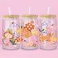 Glass can tumbler with bamboo lid and glass straw featuring an orange cat, mushrooms, bluebell flowers, ladybugs, leafy stems, and woodland cottagecore illustrations on a pink background.