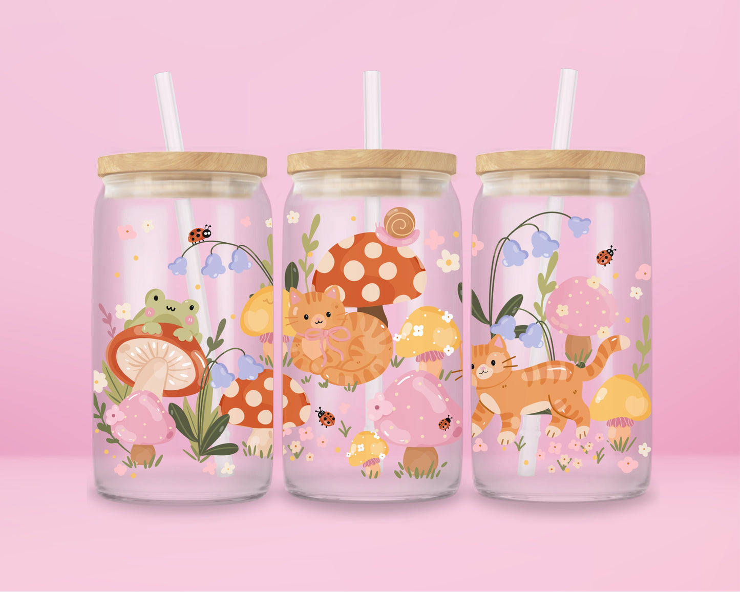 Glass can tumbler with bamboo lid and glass straw featuring an orange cat, mushrooms, bluebell flowers, ladybugs, leafy stems, and woodland cottagecore illustrations on a pink background.