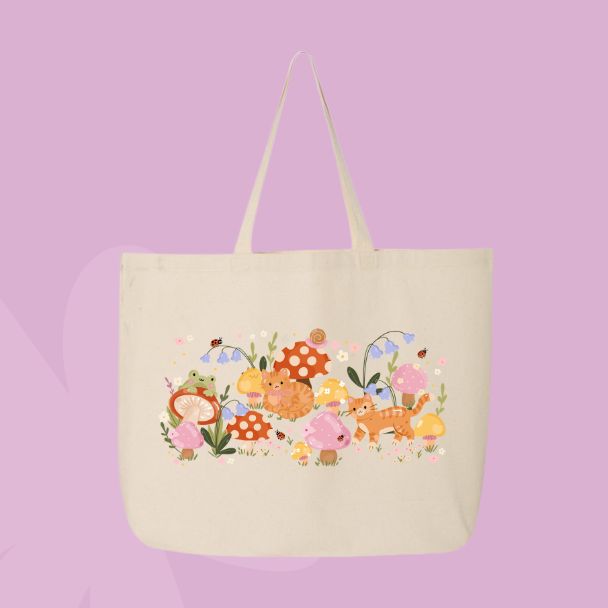 Large beige canvas tote bag featuring an orange cat, mushrooms, bluebell flowers, ladybugs, leafy stems, and woodland cottagecore illustrations.