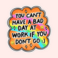 Bright orange sticker with a rainbow background and smiley faces reading “You can’t have a bad day at work if you don’t go :)”.