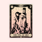 A tarot-style art print card featuring a vintage illustration of a girl bound to a pole with flames, surrounded by stars and moons. The card has a cream and black border with the text 'GIRLS WILL BE GIRLS' at the bottom, set against a solid pale pink background.