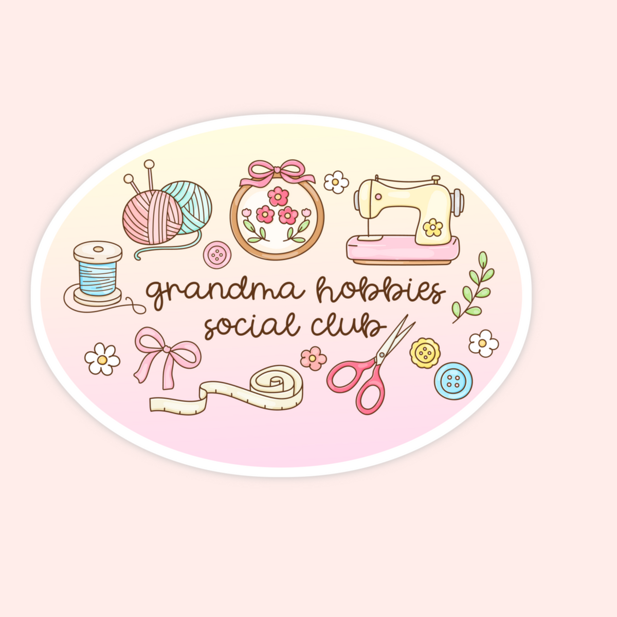 An oval sticker or decal featuring a retro-style illustration of sewing and crafting items, including yarn balls, a sewing machine, scissors, a measuring tape, flowers, and buttons, with the text 'grandma hobbies social club' in brown script. The sticker is centered on a pale pink background.