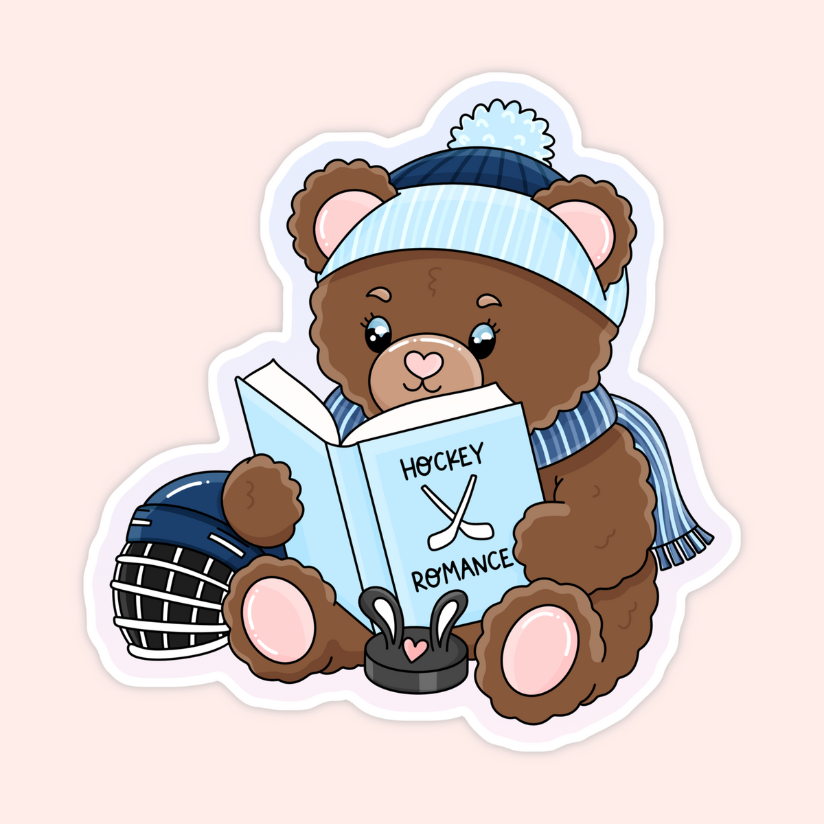A die-cut sticker featuring a cute cartoon brown teddy bear wearing a blue striped beanie with a pom-pom and a blue striped scarf, sitting and reading a light blue book that says 'HOCKEY ROMANCE'. The bear holds a hockey puck and wears a hockey helmet.