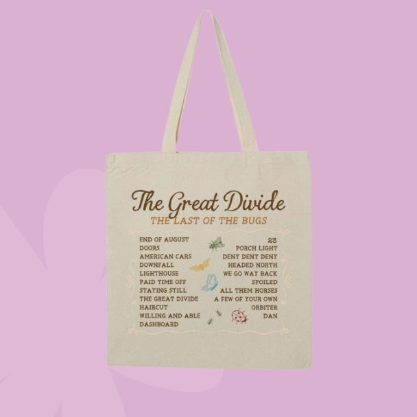 A cream-colored canvas tote bag with two handles, featuring a printed list titled 'The Great Divide: The Last of the Bugs' in brown text, set against a solid lavender background.