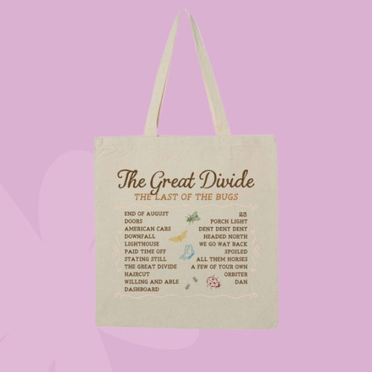 A cream-colored canvas tote bag with two handles, featuring a printed list titled 'The Great Divide: The Last of the Bugs' in brown text, set against a solid lavender background.