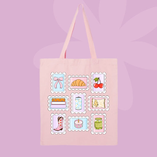 A light pink canvas tote bag with long shoulder straps, featuring a grid of nine cute, vintage-style illustrated postage stamp designs on the front. The designs include a pink bow, a croissant, cherries, a cake, a polka-dot cupcake, a cowboy boot, a jar, a book, and a map, all set against a soft lavender background with subtle leaf silhouettes.