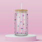 Glass cup with pastel pansies, navy blue hearts, and star sparkles on a soft pink background.
