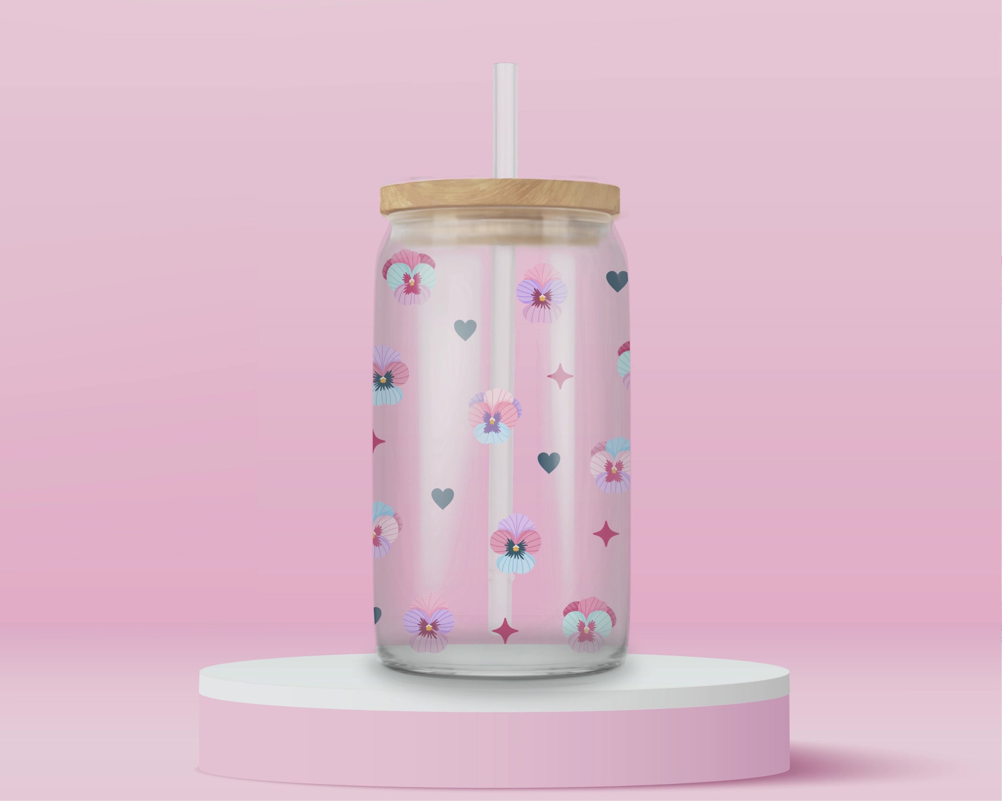Glass cup with pastel pansies, navy blue hearts, and star sparkles on a soft pink background.
