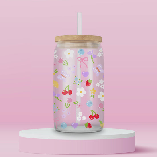 Clear glass can tumbler with a soft pink background, covered in cherries, strawberries, lemons, flowers, bows, and pastel doodles for a sweet garden-inspired look.