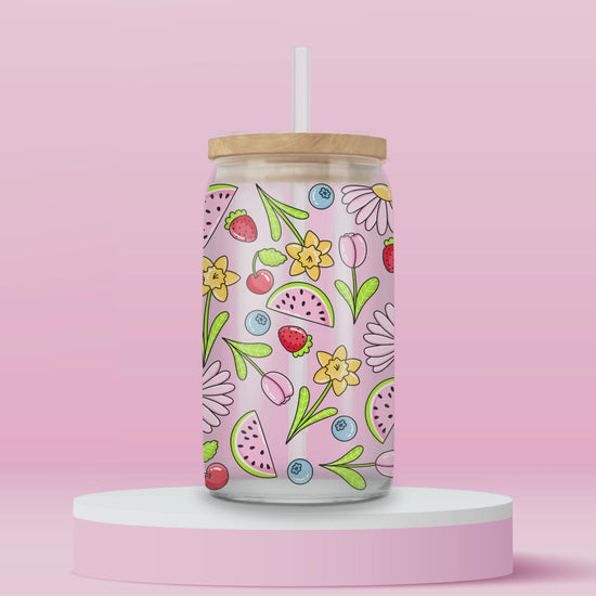 Glass cup with pink background covered in colorful fruits (watermelon, strawberries, blueberries, cherries) and spring flowers (daisies, tulips, daffodils).