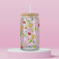 Glass cup with pink background covered in colorful fruits (watermelon, strawberries, blueberries, cherries) and spring flowers (daisies, tulips, daffodils).