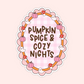 A die-cut sticker featuring a circular autumn-themed design with the text 'PUMPKIN SPICE & COZY NIGHTS' in brown lettering over a pink gingham background. The circle is decorated with cartoon pumpkins, red-and-white mushrooms, white ghosts, and an orange border, all on a pale pink background.