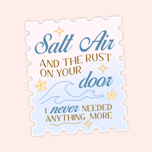 A die-cut decorative sign or sticker with a scalloped edge, featuring the phrase “Salt Air and the rust on your door I never needed anything more” in blue and gold lettering with star and wave illustrations, shown on a pale pink background.