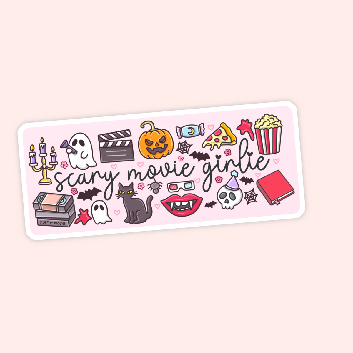A rectangular sticker with rounded corners featuring a light pink background and the phrase 'scary movie girlie' in black script. The sticker is decorated with various cute Halloween and movie-themed illustrations, including a jack-o'-lantern, vampire lips, a ghost, a clapperboard, a popcorn bucket, and a cassette tape.