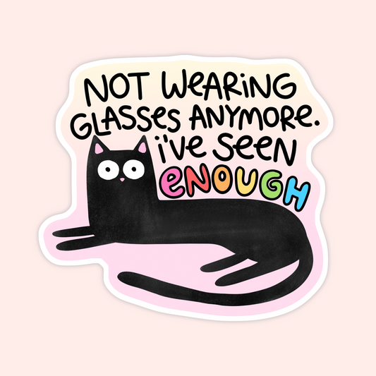 A die-cut sticker featuring a black cartoon cat lying down with the text 'NOT WEARING GLASSES ANYMORE. I'VE SEEN ENOUGH' in black and colorful lettering, shown on a pale pink background.