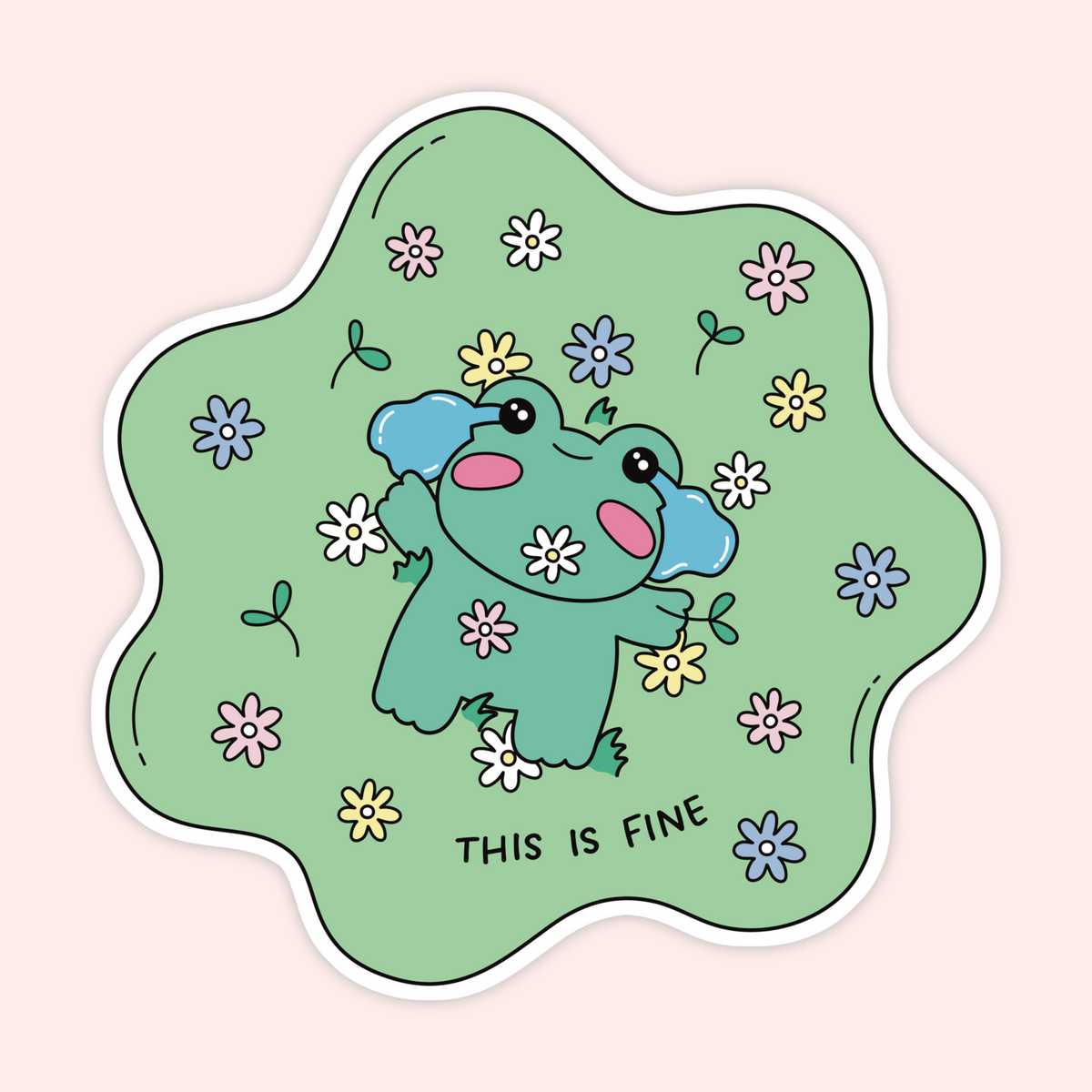 A die-cut sticker featuring a cute cartoon frog surrounded by small flowers on a light green background, with the text 'THIS IS FINE' at the bottom, shown on a pale pink background.