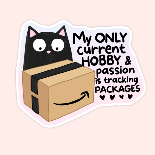 A die-cut sticker featuring a cartoon black cat peeking over a brown cardboard box with black tape and the Amazon smile logo, next to the text 'My ONLY current HOBBY & passion is tracking PACKAGES' with small heart icons, shown on a pale pink background.